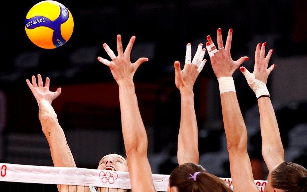 Volleyball players blocking at the net with taped fingers